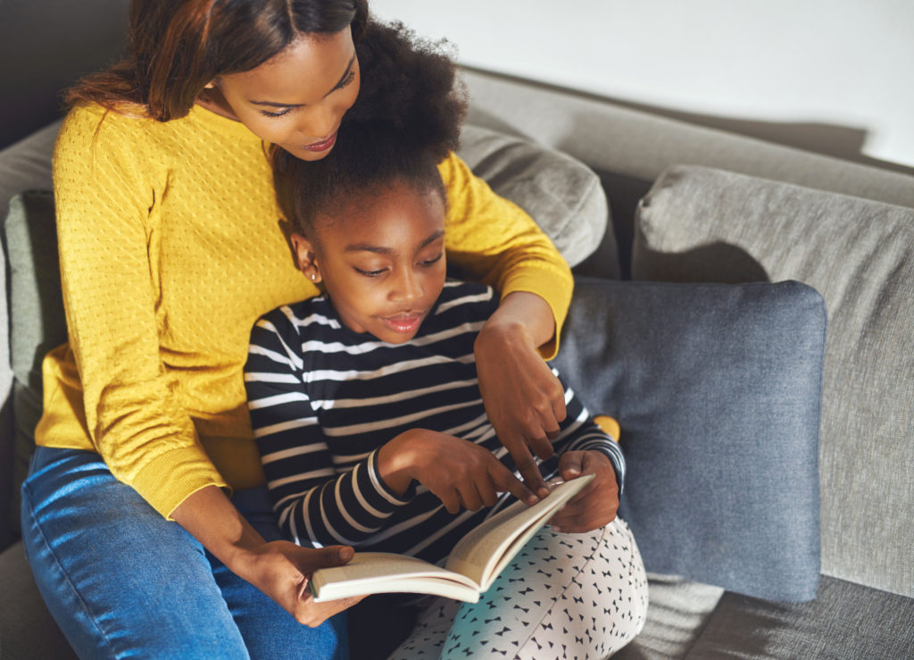 daughter learning how to read from mother