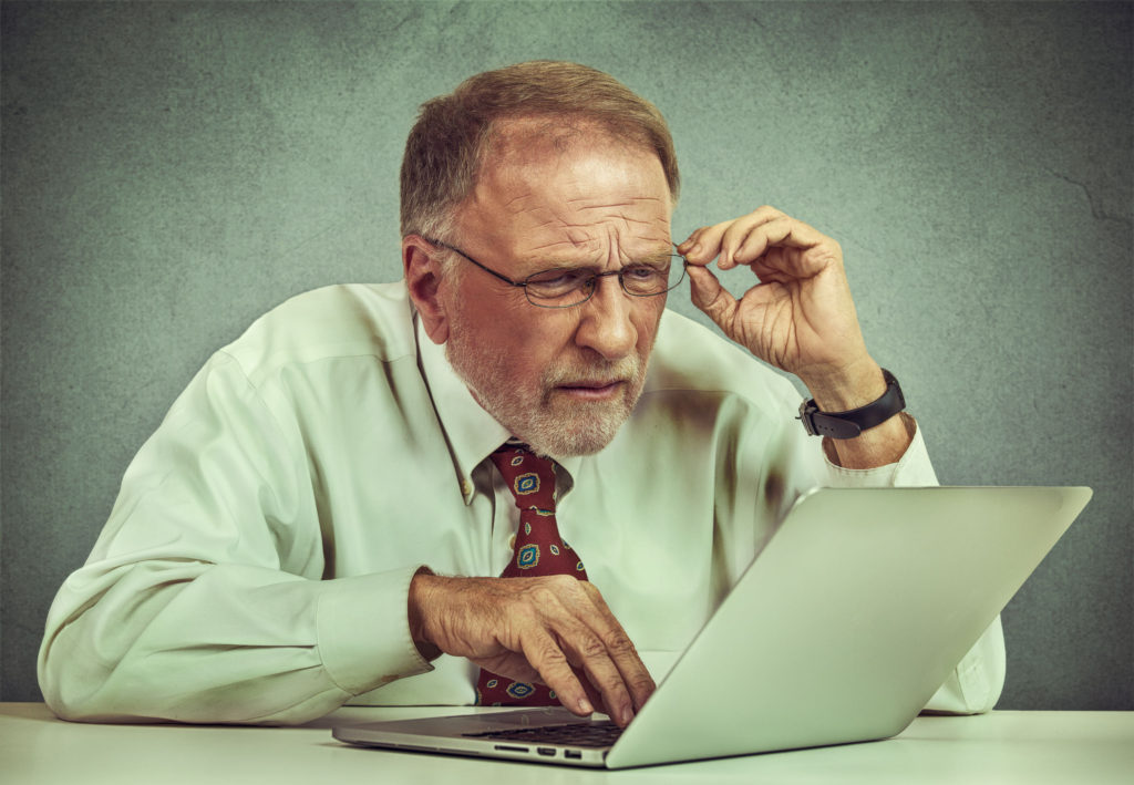 older man struggling to read on a computer